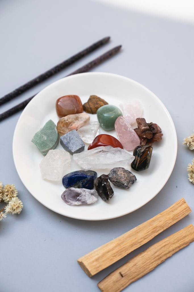 A collection of colorful healing crystals displayed on a white ceramic plate for spiritual therapy.